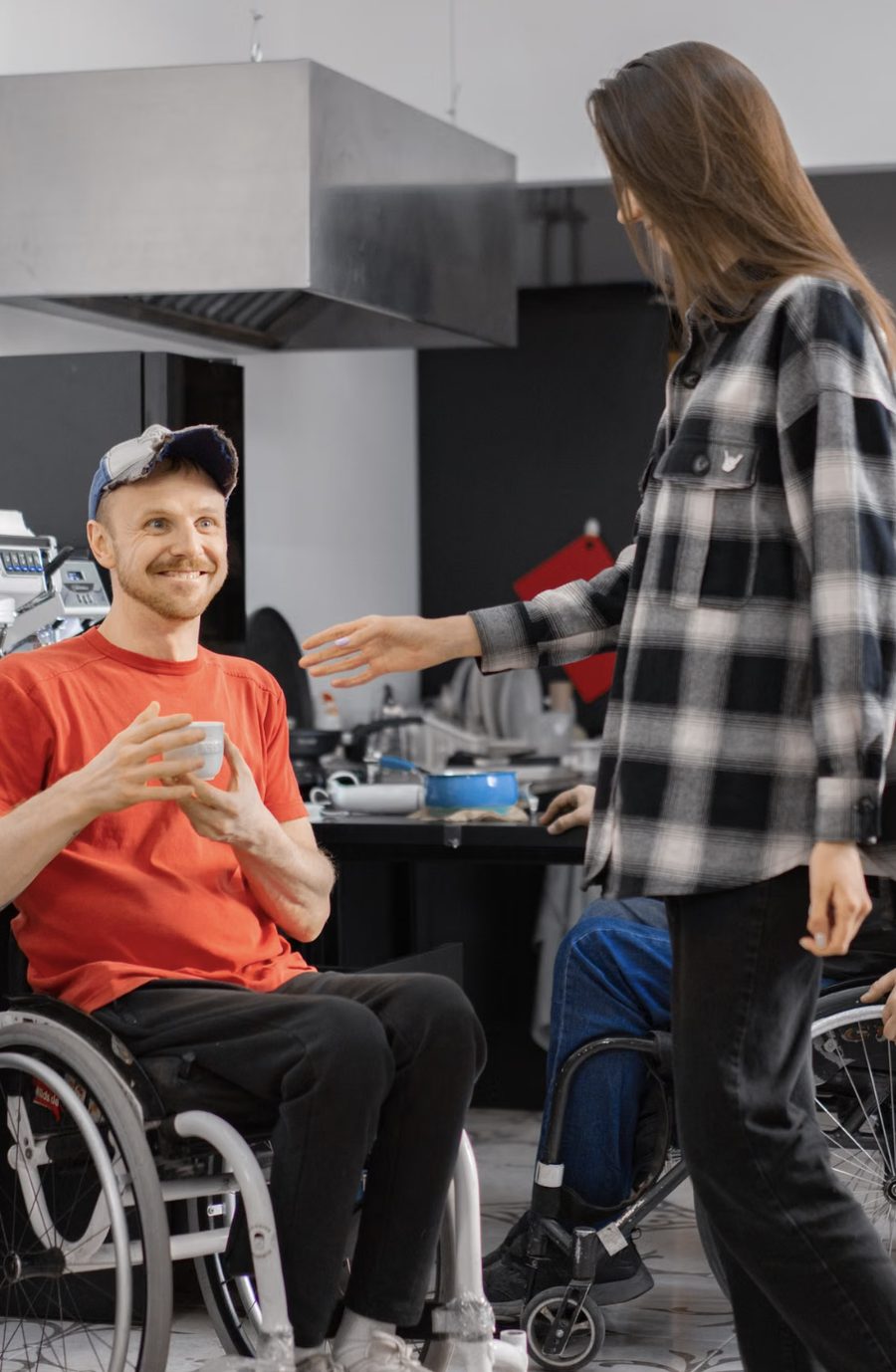 Un homme en fauteuil roulant, une tasse à la main, échange avec une femme